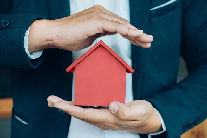 business_man_hand_hold_house_model_saving_small_house